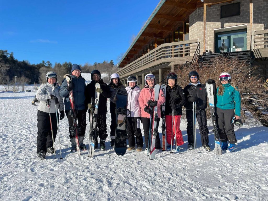 Lab members gathered at ski hill in front of lodge, wearing ski gear.